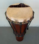 An ashiko hand drum with a ripped goatskin drumhead.