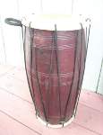 A repaired dholak, standing upright.