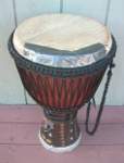 African djembe hand drum with a torn drum head taped up.