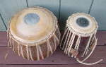A tabla dayan and tabla bayan with a broken strap and damaged drum heads.