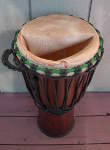 Stave djembe with a torn goat skin drum head.
