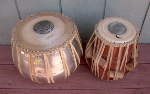 A tabla dayan and tabla bayan with a broken straps and damaged drum heads.