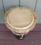 An old ashiko hand drum with a damaged drum head.