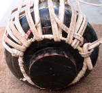 Partially removed strap attached to the counter ring at the bottom of a tabla.