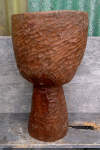 Djembe shell roughly carved asymmetically with coarse strokes.